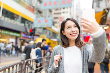 Woman taking selfie by cellphone in Hong Kongの写真素材