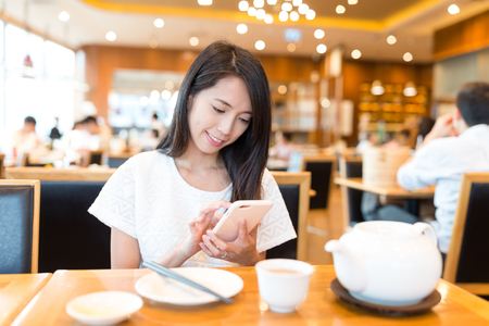 Woman use of mobile phone in restaurantの写真素材