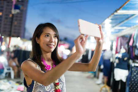 Woman taking selfie at night market in thailandの写真素材