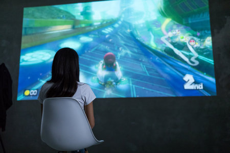 Hong Kong, 19 May 2017 -:Woman playing mario kart 8 on Nintendo Switch console over big screen