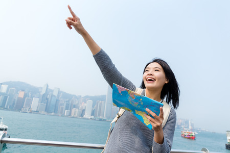Woman looking far away and holding map in Hong Kongの写真素材