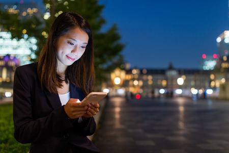 Business woman working on mobile phone at nightの写真素材