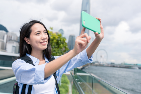 Woman taking photo on cellphone in Hong Kongの写真素材