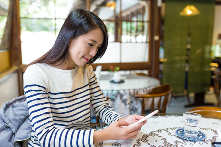 Woman using mobile phone in cafeの写真素材