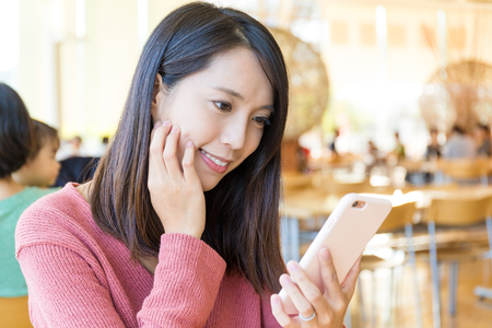 Woman using mobile phone at restaurantの写真素材
