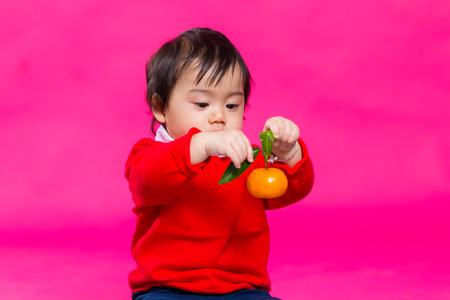 Cute chinese baby holding a tangerineの写真素材