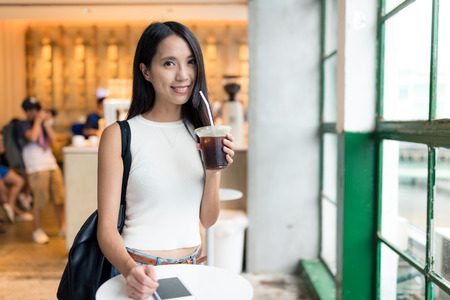 Woman enjoy her iced coffee at open air coffee shop in Hong Kongの写真素材