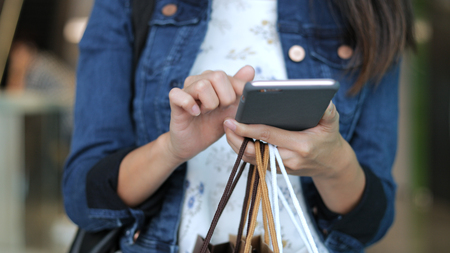 Woman holding shopping bags and using cellphoneの写真素材