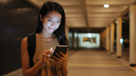 Woman using mobile phone in the city at nightの写真素材