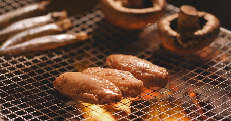 Barbecue with chicken wing, mushroom and capelin fish on grilled net at outdoor 