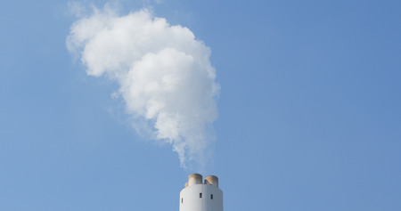 Chimney emit smoke over blue sky 