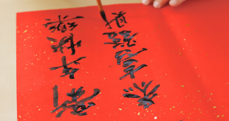 Writing Chinese calligraphy on red paper for lunar new year の写真素材