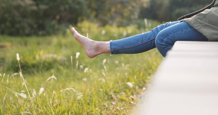 Woman sitting on wooden path under sunlight の写真素材