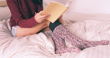 Woman read book on bed with red dressの写真素材