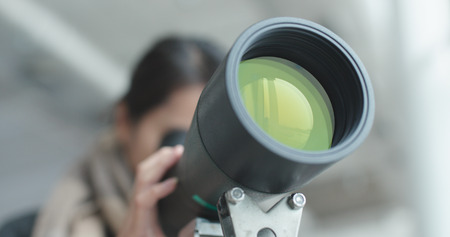 Woman looking through telescope to observe the bird habitat の写真素材
