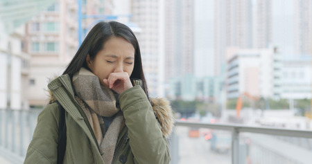 Woman sneezing at outdoor の写真素材