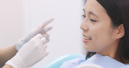 Dentist teaching patient how to use dental floss の写真素材