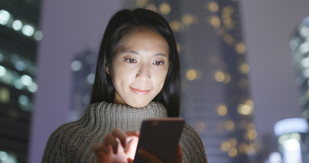 Business Woman sending sms on cellphone at night の写真素材
