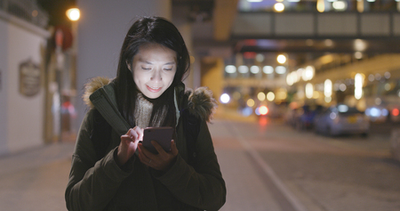 Woman using smart phone at night の写真素材
