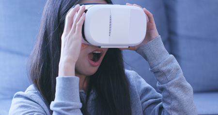 Woman wearing virtual reality device at home 