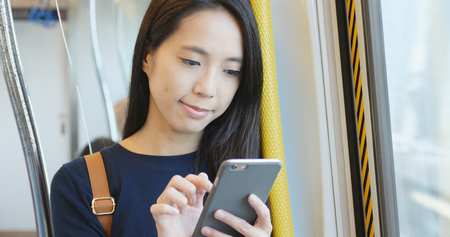 Woman working on mobile phone, mobile office concept, using cellphone for replying customer message on train compartment の写真素材