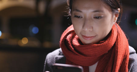 Businesswoman use of mobile phone in city at nightの写真素材