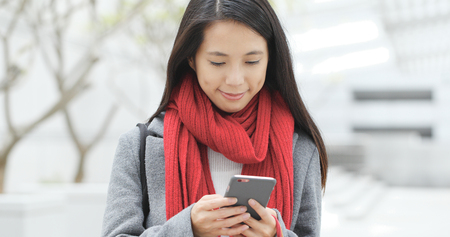 Woman look at mobile phone at outdoor の写真素材