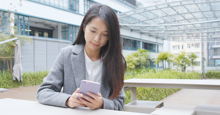 Businesswoman using mobile phone over green background の写真素材