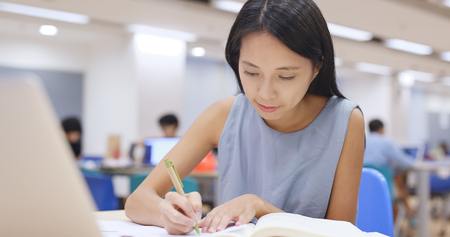 Woman working on homework in library の写真素材