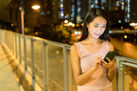 Asian woman watching on cellphone at night の写真素材