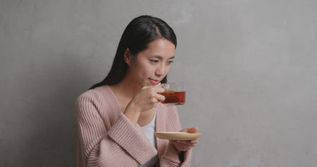 Woman having tea over gray background の写真素材