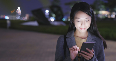 Young Woman use of cellphone in city at night の写真素材