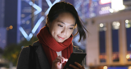 Business woman use of mobile phone in city at nightの写真素材