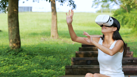 Woman watching with VR device at the park の写真素材