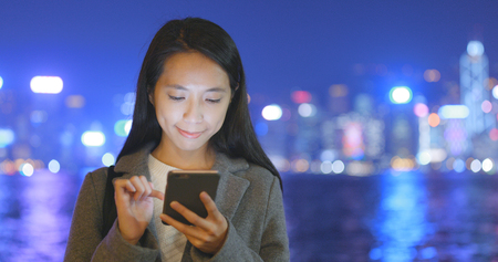Businesswoman use of mobile phone in Hong Kong at night の写真素材