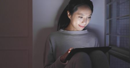 Woman use of tablet computer at night の写真素材
