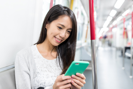Woman use of cellphone and taking MTR in Hong Kongの写真素材