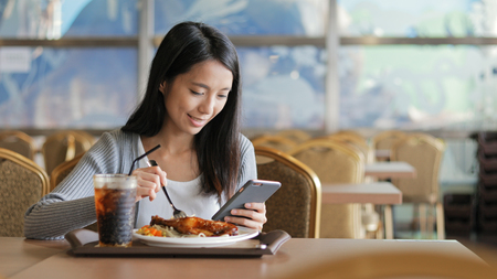 Busy woman having lunch and using cellphone の写真素材