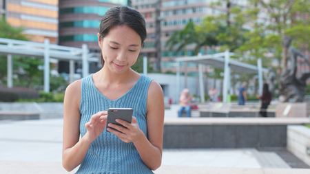 Woman use of mobile phone in the park の写真素材