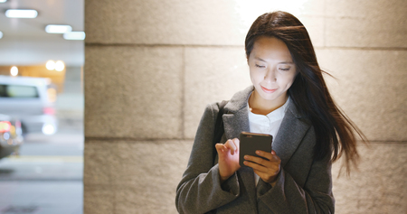 Asian business woman use of mobile phone at night の写真素材