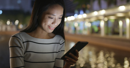 Woman use of smart phone in Hong Kong at nightの写真素材