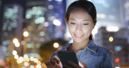 Woman using mobile phone in Hong Kong at night の写真素材