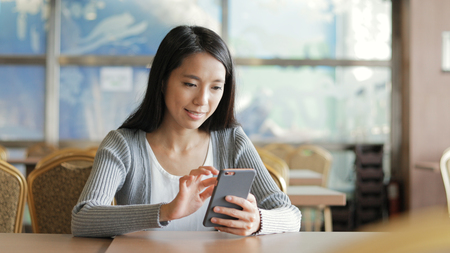 Woman using cellphone in restaurant の写真素材