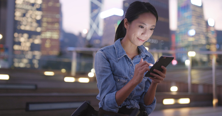 Woman sending sms on cellphone at night の写真素材