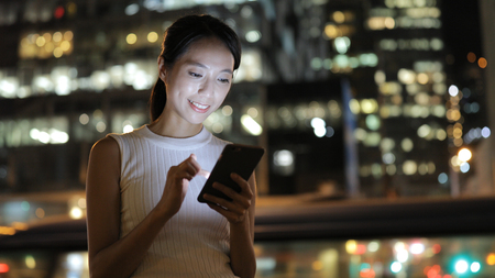 Woman working on cellphone at night の写真素材