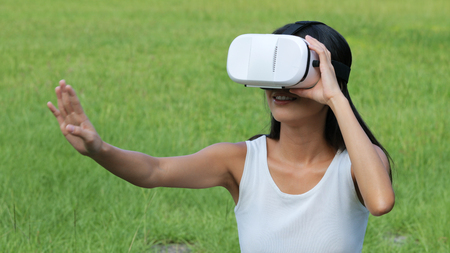 Woman watching with VR device and sitting at outdoor の写真素材