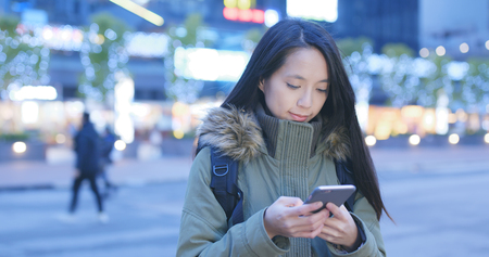 Woman use of mobile phone in city at night の写真素材