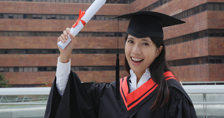 Excited Woman with graduation gown の写真素材