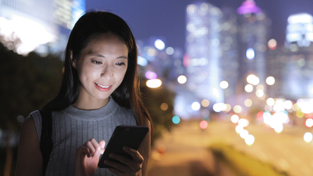 Woman sending sms on cellphone in city の写真素材