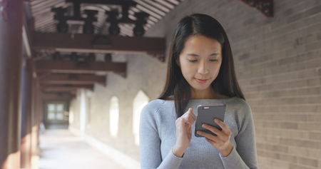 Woman using mobile phone in chinese garden の写真素材